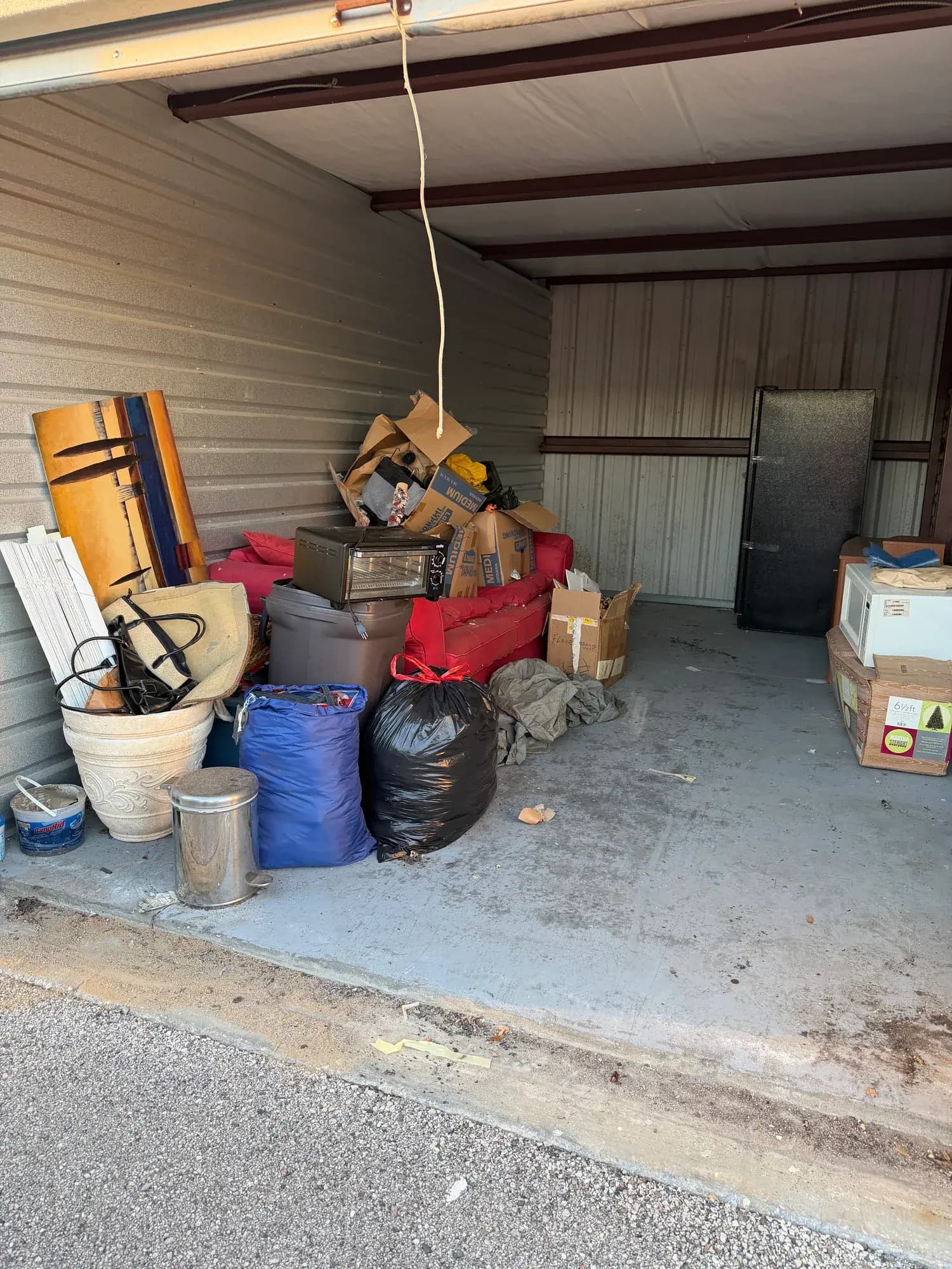Before: a storage unit in Clermont, FL packed to the door with a couch, boxes and planters