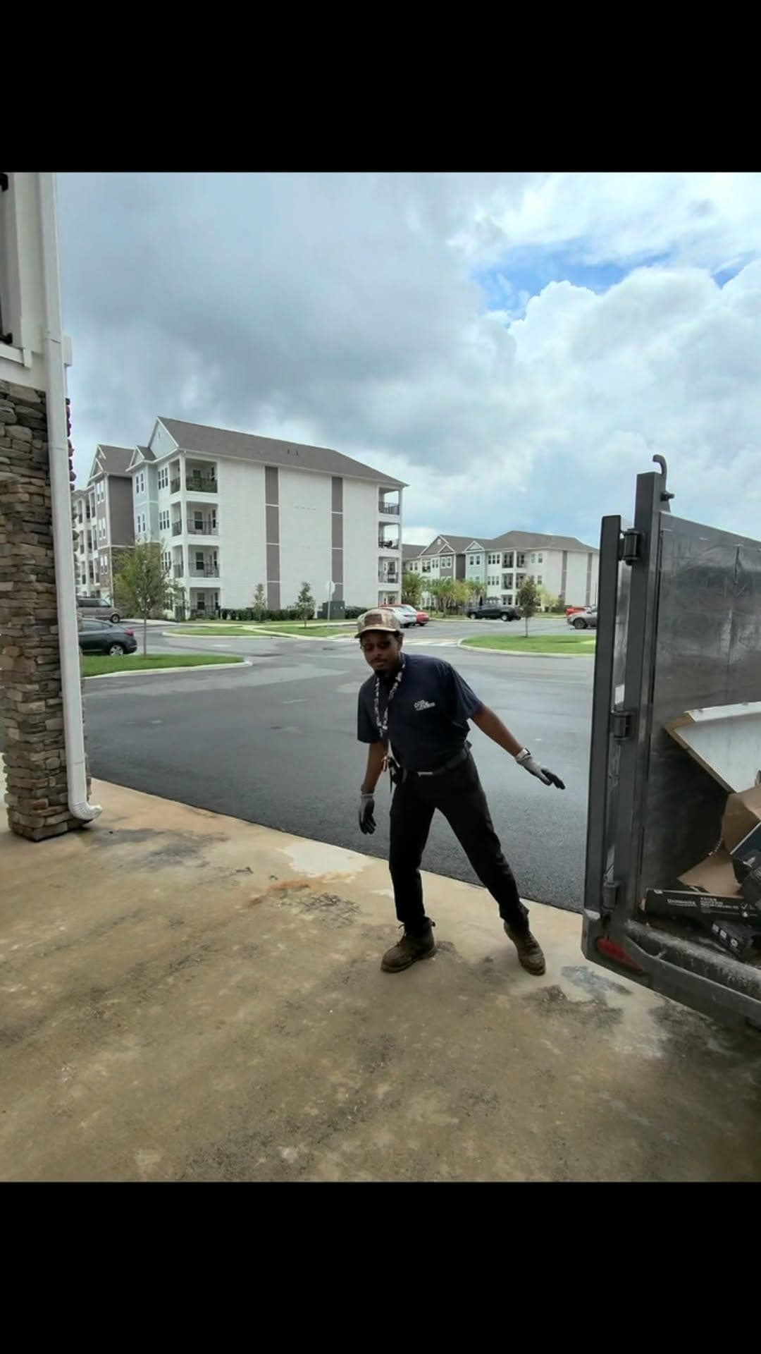 Big Rob's Hauling crew member at the dump trailer gate in a Central Florida apartment parking lot