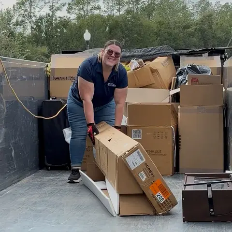 Sarah of Big Rob's Hauling loading a pile of moving boxes onto a dump trailer in Davenport, FL