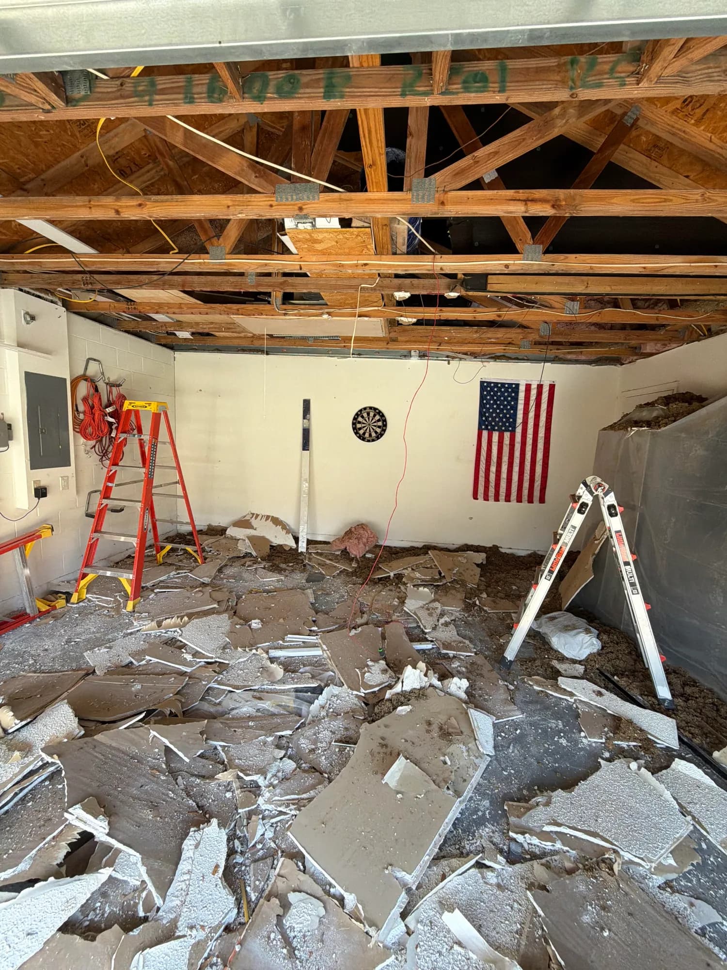 Interior demo by Big Rob's Hauling in Central Florida: garage ceiling drywall down to the trusses, debris on the floor for haul-out