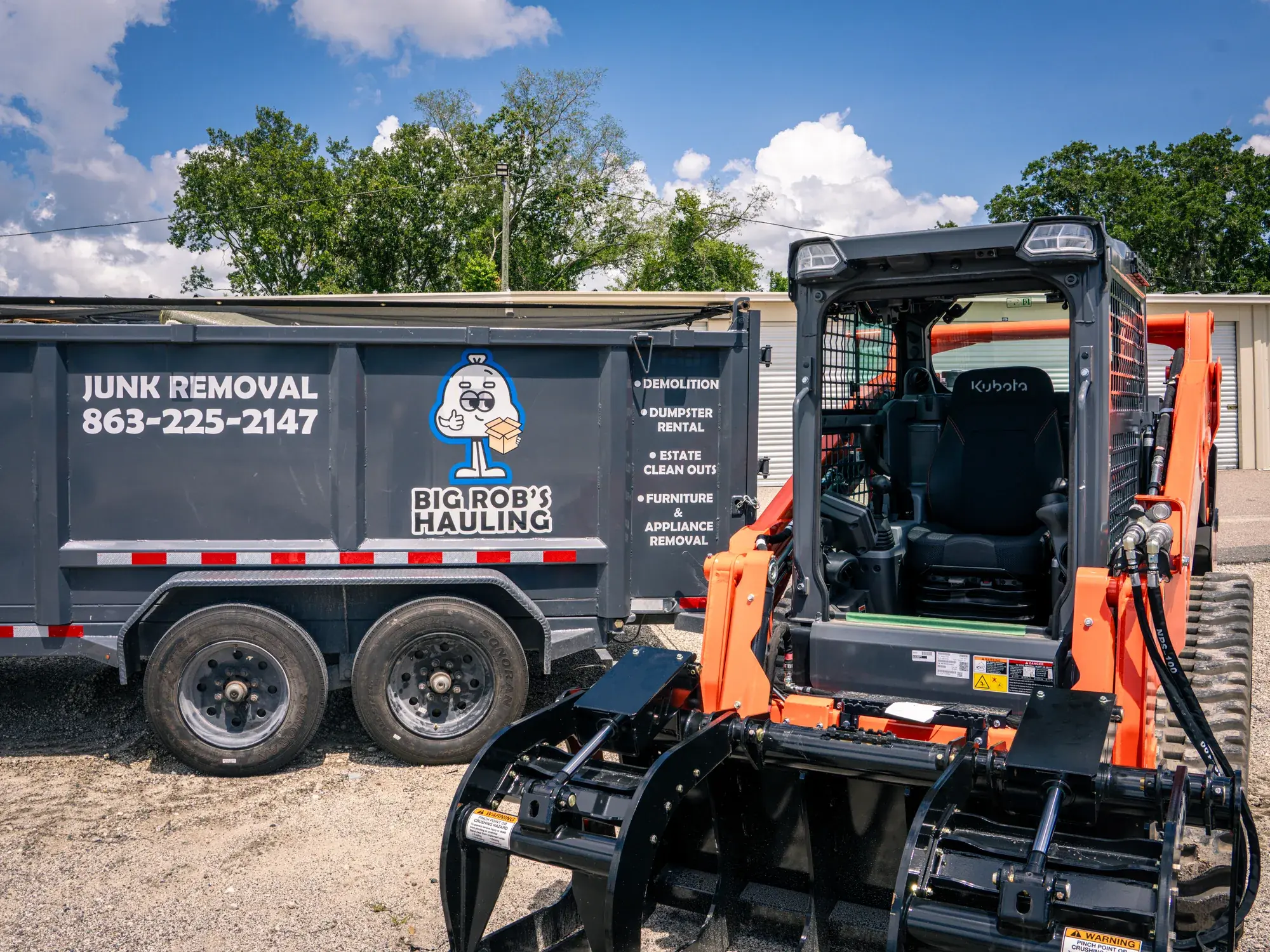 Kubota compact track loader with grapple beside a Big Rob's Hauling Junk Removal dump trailer in Davenport, FL