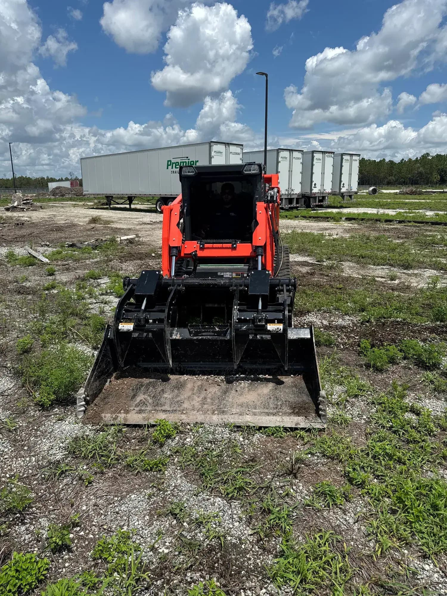 Big Rob's Hauling Kubota track loader on the flatbed at a Polk County, FL field job