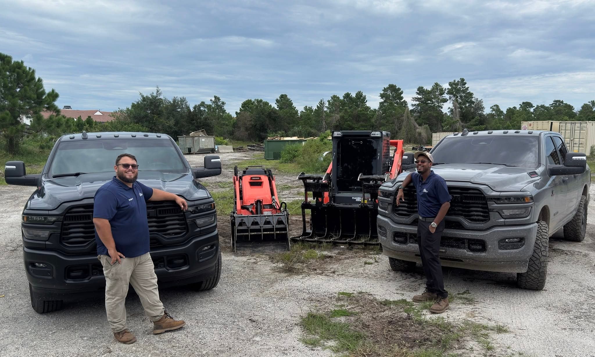 Rob and a Big Rob's Hauling crew member with two Ram trucks and skid steer attachments in Davenport, FL