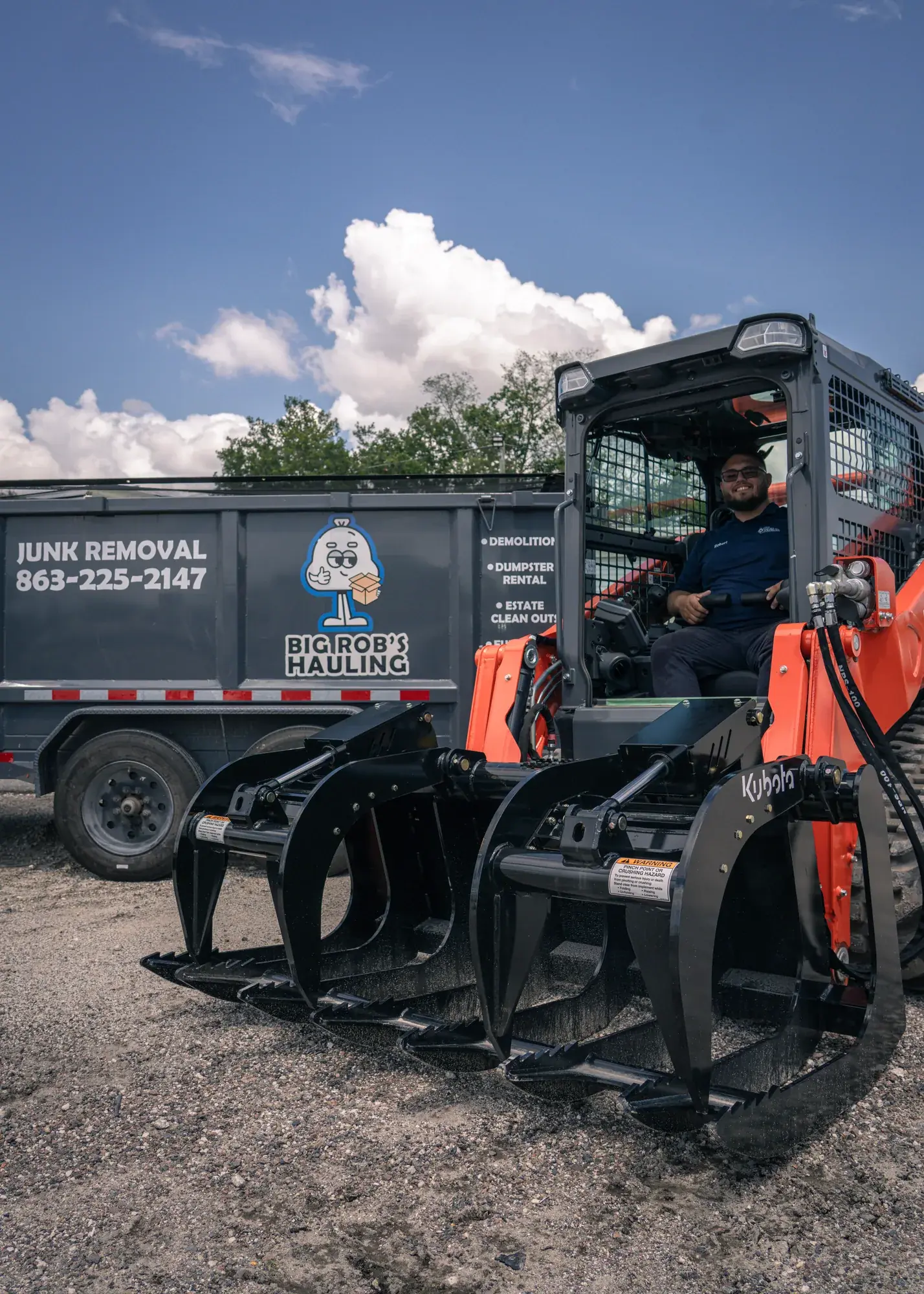 Rob at the controls of the Kubota compact track loader with grapple, Big Rob's Hauling trailer behind, Davenport, FL
