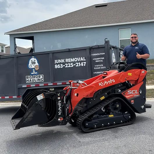 Rob, owner of Big Rob's Hauling, giving a thumbs up beside a dump trailer and Kubota skid steer at a Davenport, FL home
