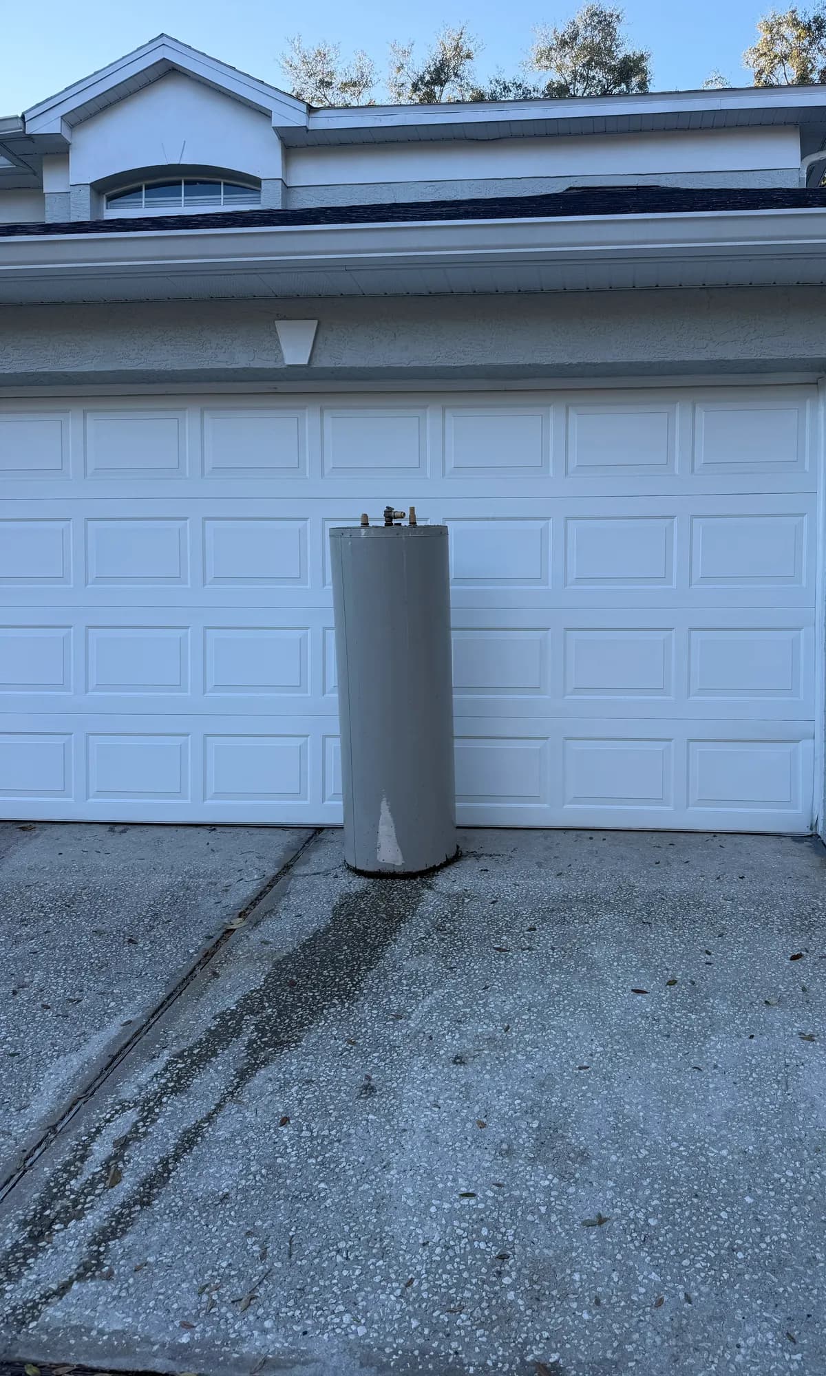 An old water heater set out at the garage door for Big Rob's Hauling appliance pickup in Ocoee, FL